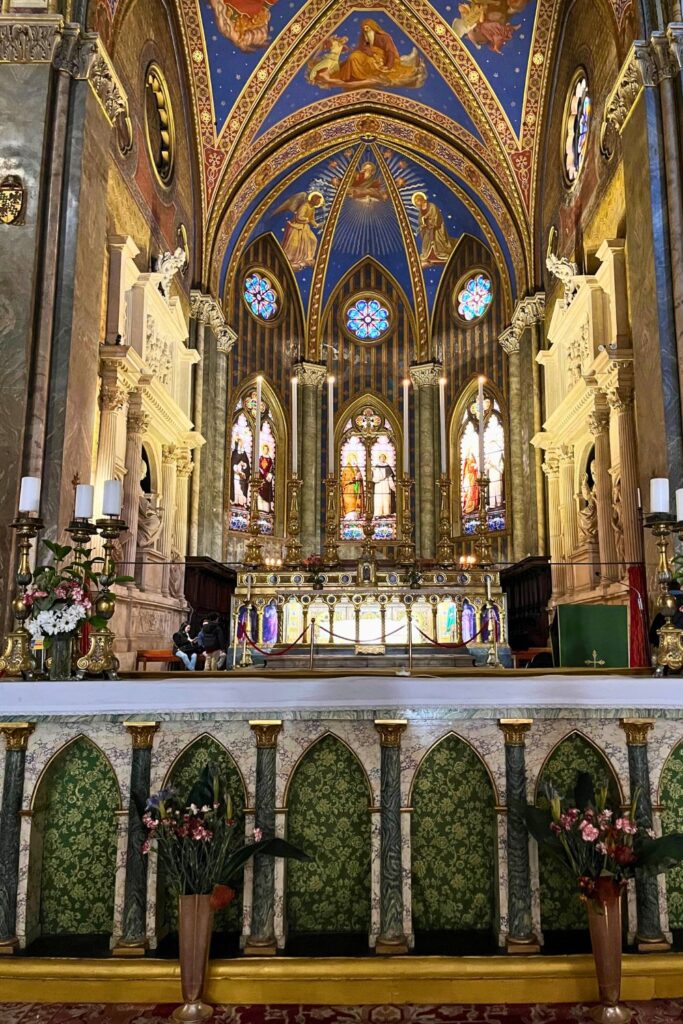 Altar principal da Basílica de Santa Maria sopra Minerva com vitrais coloridos e detalhes góticos em dourado.