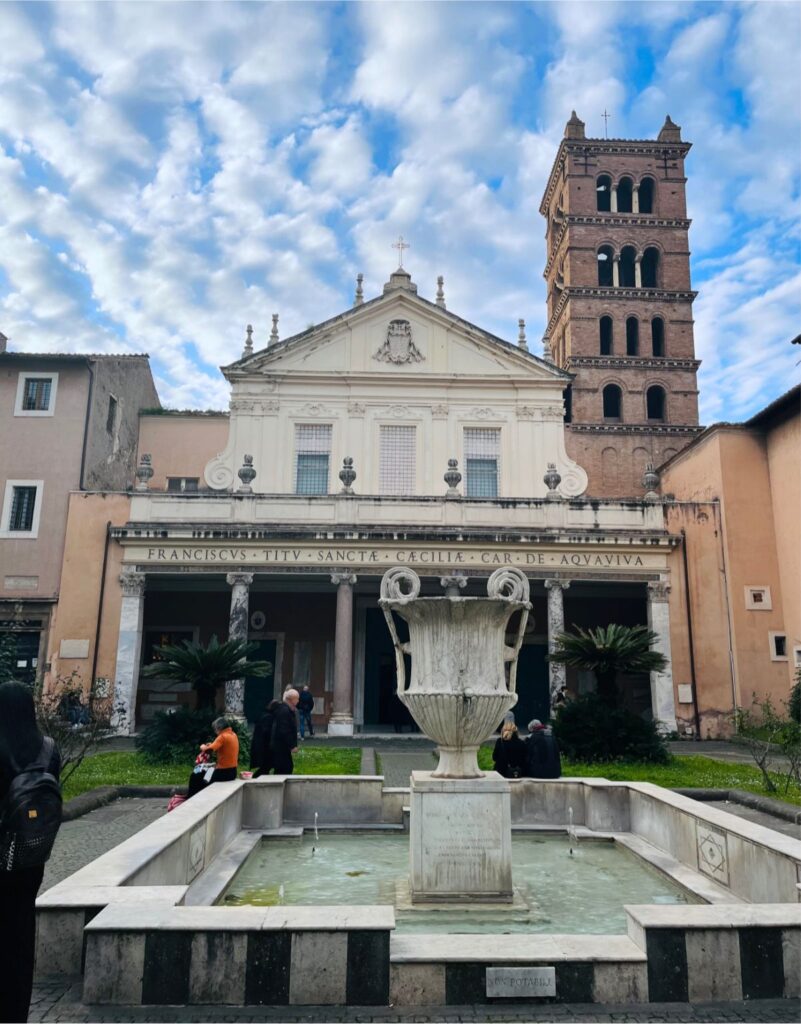 Fachada da Basílica de Santa Cecília em Trastevere, com campanário e fonte de água.