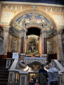 Mosaico do Ábside da Basílica de Santa Prassede em Roma, retratando Cristo em glória cercado por santos e anjos, acima do altar central.