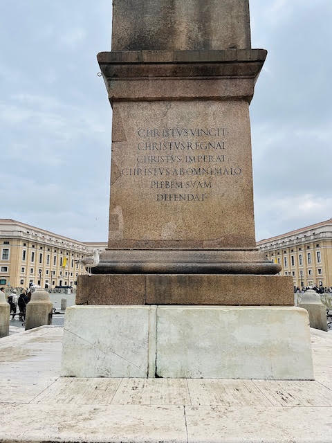 Inscrição latina na base do obelisco da Praça de São Pedro proclamando o reinado de Cristo