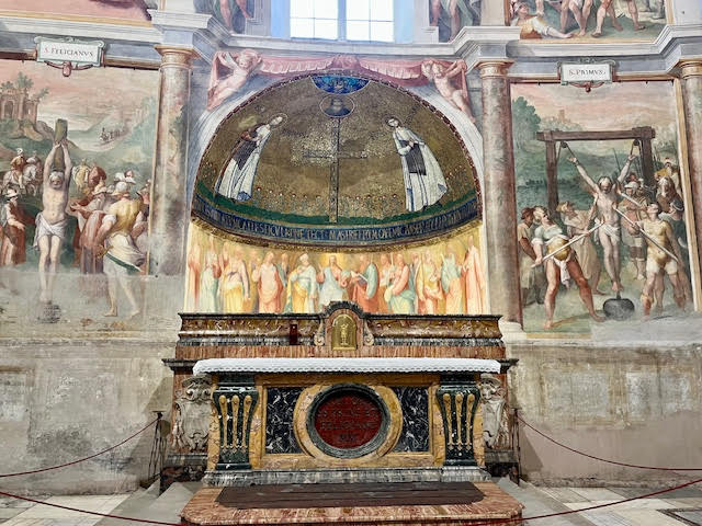Capela dos mártires Primo e Feliciano em Santo Stefano Rotondo al Celio, com afrescos do martírio e estrutura circular da basílica.