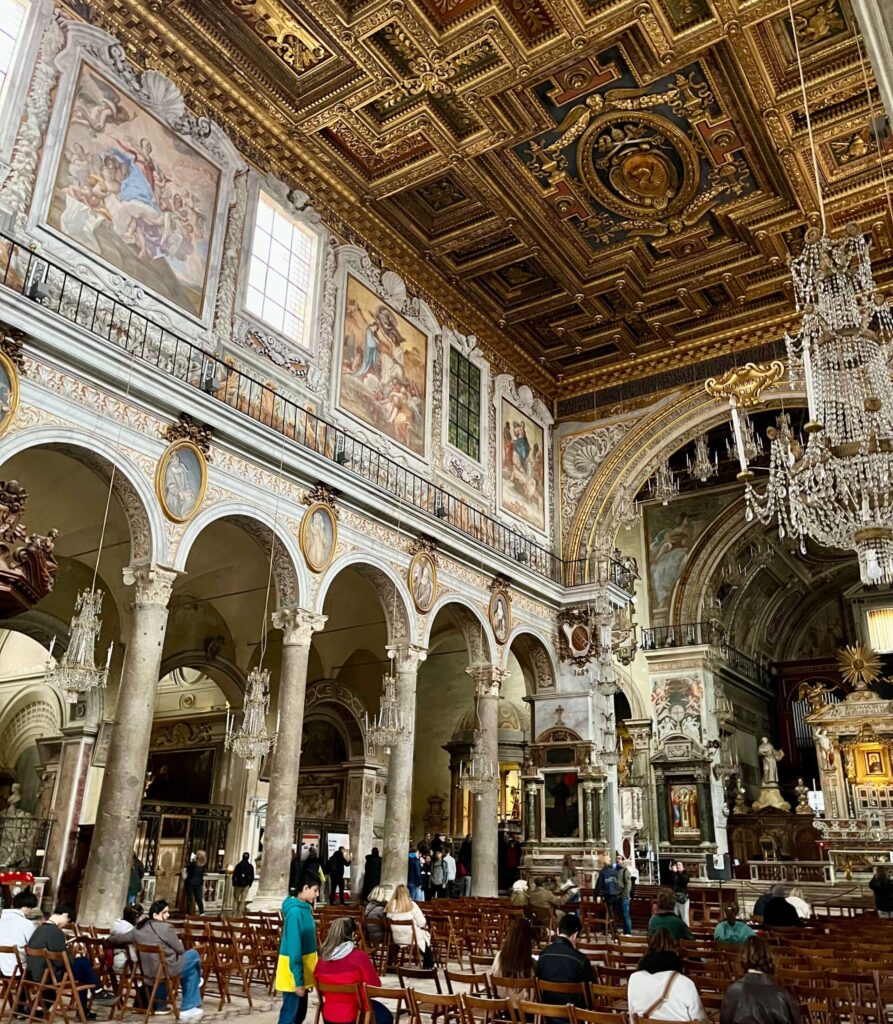 Interior da Basílica de Santa Maria in Aracoeli com teto dourado e colunas históricas em Roma.