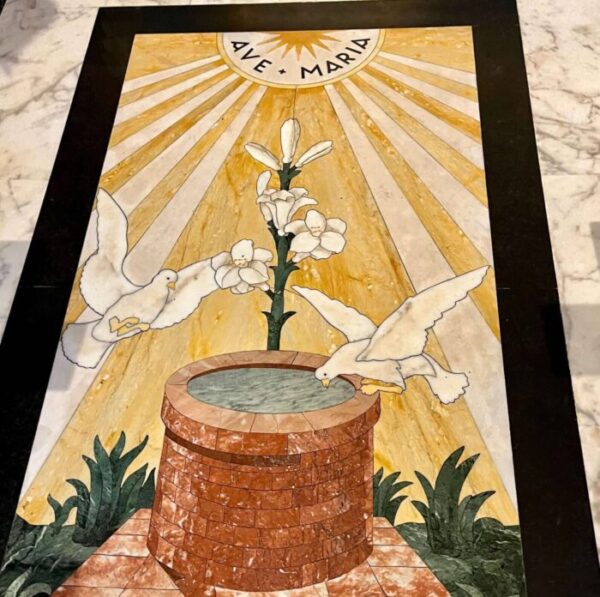 Painel em opus sectile no piso da Capela da Madonna del Pozzo, em Santa Maria in Via, representando o poço do milagre, duas pombas e um lírio sob a saudação "Ave Maria"